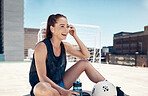 City sports, fitness and woman sitting to relax with water, ball and earbuds. Workout, rest and happy rooftop exercise, fun with urban soccer training and music streaming app in headphones in summer.