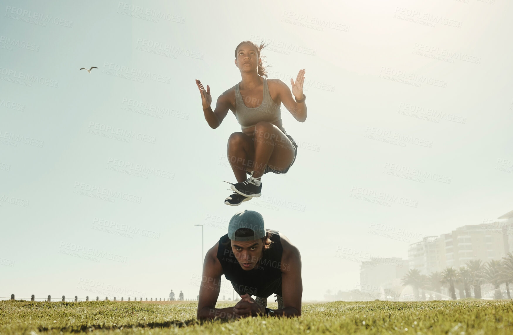 Buy stock photo Energy, training and intense couple workout in a park with serious, cool and wellness in nature. Cross, different and fit jumping woman with man doing ground pushup in extreme physical exercise 