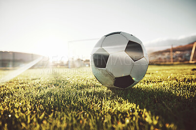 Buy stock photo Soccer, sports and ball on field for game with sunshine on green grass for tournament match. Football, cardio and competition day with foreground and sunlight flare on athletic ground.


