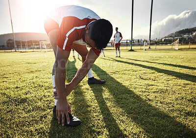 Buy stock photo Football, athlete and man doing a stretching exercise for legs on a sport field before a match. Sports, fitness and healthy guy doing a warm up workout at soccer training on a pitch for a game.