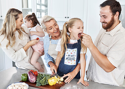 Buy stock photo Family, feeding and tomato with a girl and father eating a health snack in the kitchen of their home while cooking together. Food, health and diet with a man giving his daughter a healthy snack