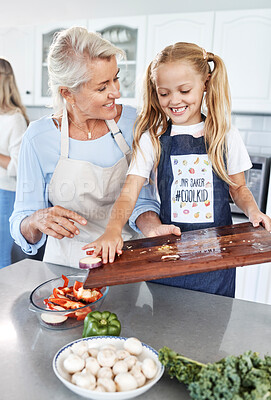 Buy stock photo Children, family and cooking with a girl and grandmother preparing a meal in the kitchen of their home together. Food, love and learning with a senior woman teaching her granddaughter about cooking