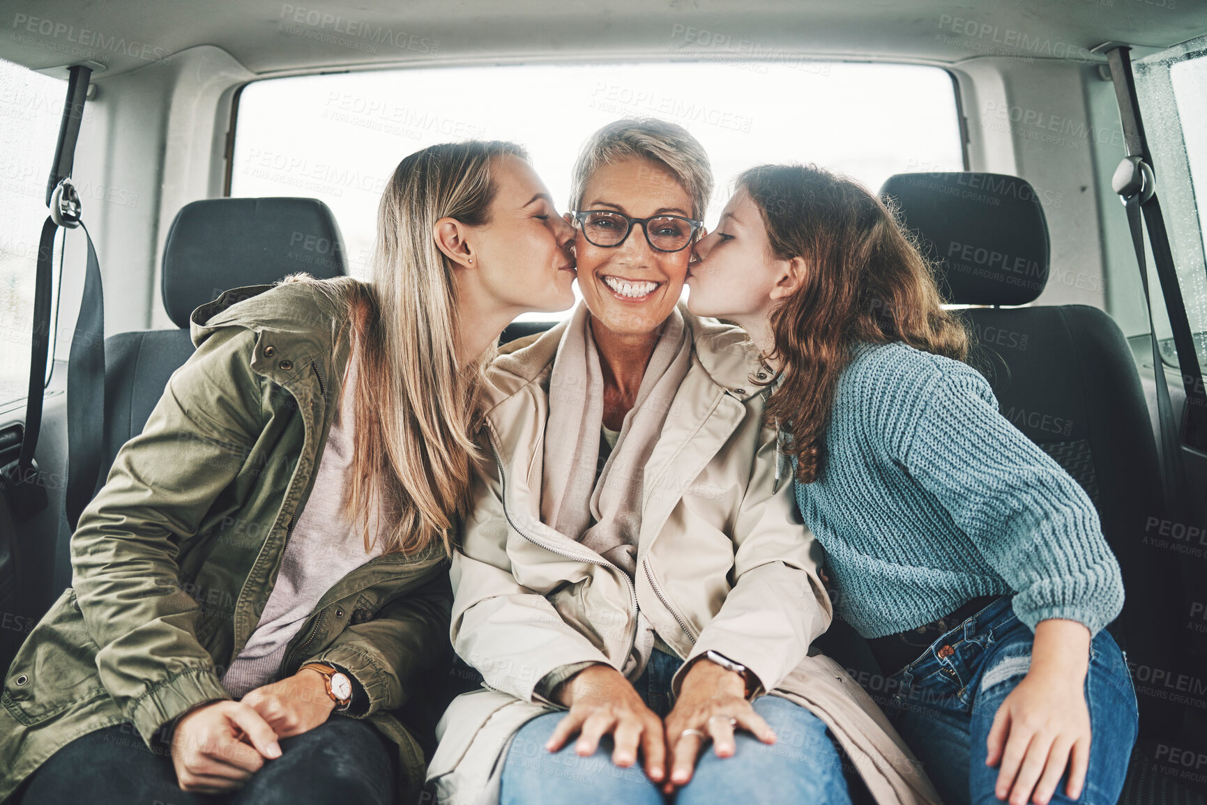 Buy stock photo Family, kiss and road trip with a girl, mother and grandmother in the backseat of a car for a drive. Love, travel and transport with a senior woman, daughter and granddaughter on vacation or holiday