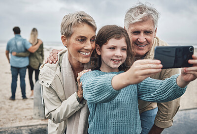 Buy stock photo Phone, selfie and grandparents with a child at the beach while on family adventure, journey or holiday. Happy, smile and senior couple in retirement taking picture with girl while on seaside vacation