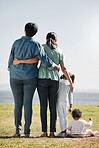 Park, nature and back view of family on grass outdoors with relatives spending quality time together. Love, support and caring grandma, mom and girl with baby bonding together with scenic ocean view.