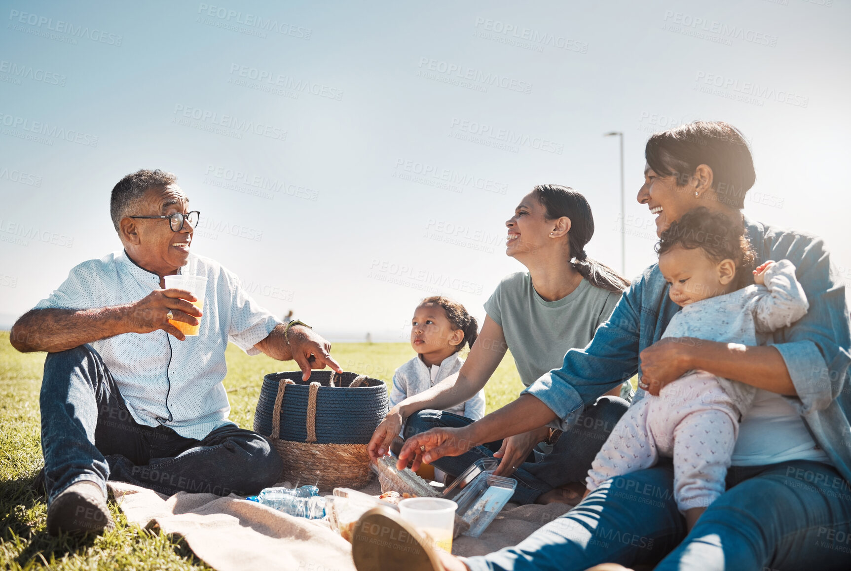 Buy stock photo Picnic, juice and big family relax on grass for summer holiday, outdoor wellness and healthy lifestyle together with blue sky mock up. Grandparents, mother and children with food basket in field park