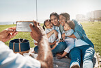 Phone, family and picnic with children, parents and grandparents posing for a photograph on a field by the beach. Kids, mobile and love with the hands of a man taking a picture of his relatives