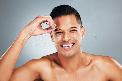 Buy stock photo Portrait of a man tweezing his eyebrow with a tweezer in studio with gray background. Happy, smile and young guy plucking brow for hair removal for grooming, cleaning and hygiene routine or self care