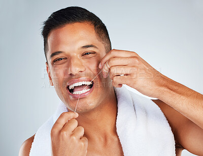 Man, dental flossing and teeth with smile for clean hygiene and health against a grey studio background. Portrait of happy toothy male smiling in fresh grooming and floss for mouth, oral and gum care