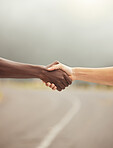 Handshake, success and hands with diversity, support and teamwork partnership on a road. Hand together of friends, workers or people showing motivation solidarity, faith trust and hope outdoor