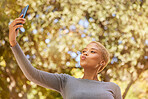 Selfie, phone and of woman in nature park relax, happy and smile while in outdoor forest for peace, quiet and freedom. Happiness, trees and calm girl taking picture to post to online social media app