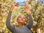 Black woman, phone and selfie with pout in park with sunshine, summer and happiness by trees. Woman, smartphone and lips in kiss for photo, outdoor and nature with face in happy, funny and relax time