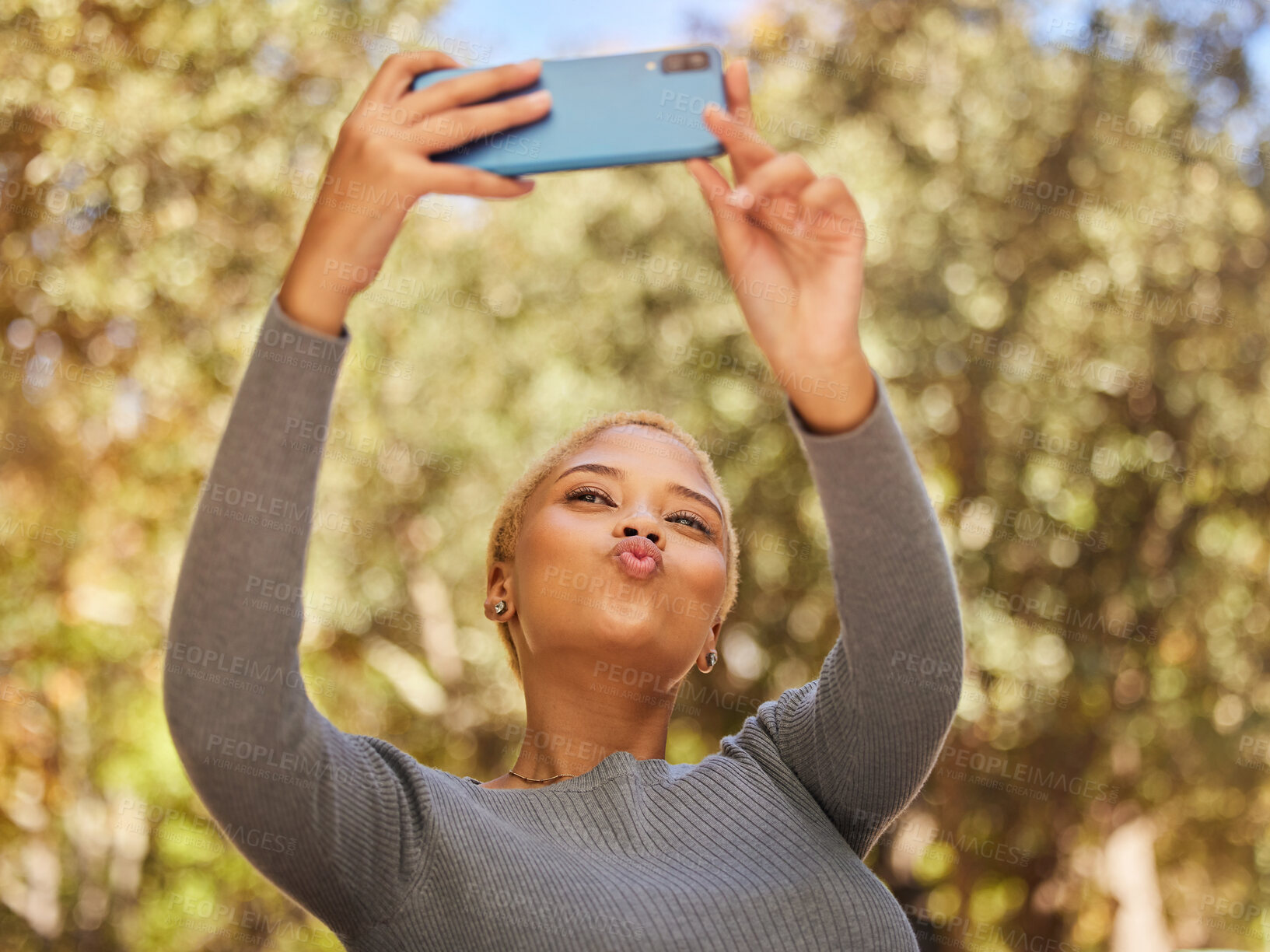 Buy stock photo Black woman, phone and selfie with pout in park with sunshine, summer and happiness by trees. Woman, smartphone and lips in kiss for photo, outdoor and nature with face in happy, funny and relax time