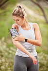 Woman, arm band and phone for fitness in nature park or environment forest woods for workout, training and exercise. Runner, sports person and athlete with mobile technology for health data tracking