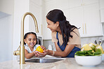 Vegetable, family and washing with a girl and mother cleaning a yellow pepper in the kitchen of their home together. Kids, health and love with a woman and daughter using a basin to rinse a veggie