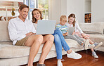 Family, couple and kids with digital devices have smile, together and being happy in living room on couch. Children, parents and love with laptop, smartphone and bonding together in lounge on sofa.