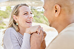 Beach, holding hands and man propose to woman on holiday by sea, happy and smiling together. Affection, romance and multicultural couple by ocean, enjoying vacation and bonding on weekend in summer