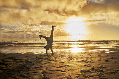 Buy stock photo Sunset, silhouette and child doing cartwheel at the beach having fun, playing and enjoy nature. Freedom, inspiration for youth and kid doing handstand by ocean on summer vacation, holiday and weekend