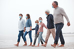 Covid, mask and big family walking together on a beach with mother, father and children outdoor. Parents, kids and grandparents walking on sand at the ocean water waves holding hands with love
