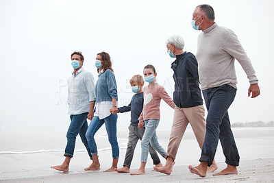 Buy stock photo Covid, mask and big family walking together on a beach with mother, father and children outdoor. Parents, kids and grandparents walking on sand at the ocean water waves holding hands with love