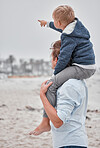 Travel, family and father with son at a beach, having fun while carrying child on shoulders and enjoying the view in Mexico. Parent, kid and hand of boy pointing to cloudy sky while on a sea vacation