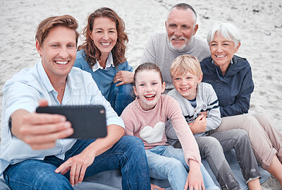 Buy stock photo Family, generations and selfie, together and happy on outdoor adventure at beach, smartphone and technology. Parents, grandparents and children smile, spending quality time and bonding at the coast.