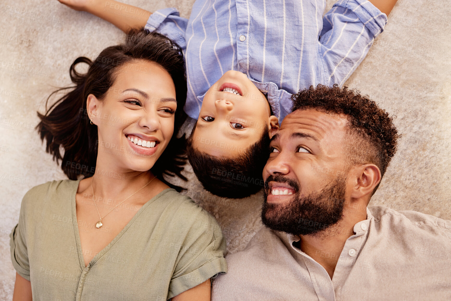 Buy stock photo Love, family and floor fun on carpet in a living room with happy, relax and smile parents and boy bonding from above. Black family, face and mother with father and child lying on ground of their home