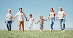 Family, love and walking. with smile, together and happy on a field in nature with a blue sky background. Big family with kids, parents and grandparents enjoy weekend, holiday and summer in Germany  