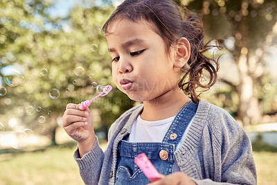 Buy stock photo Nature, fun and a girl blowing bubbles in an outdoor park on a happy summer weekend. Sun, fun and a blow a soap bubble, freedom playing in the garden, a cute child in field with trees and sunshine.