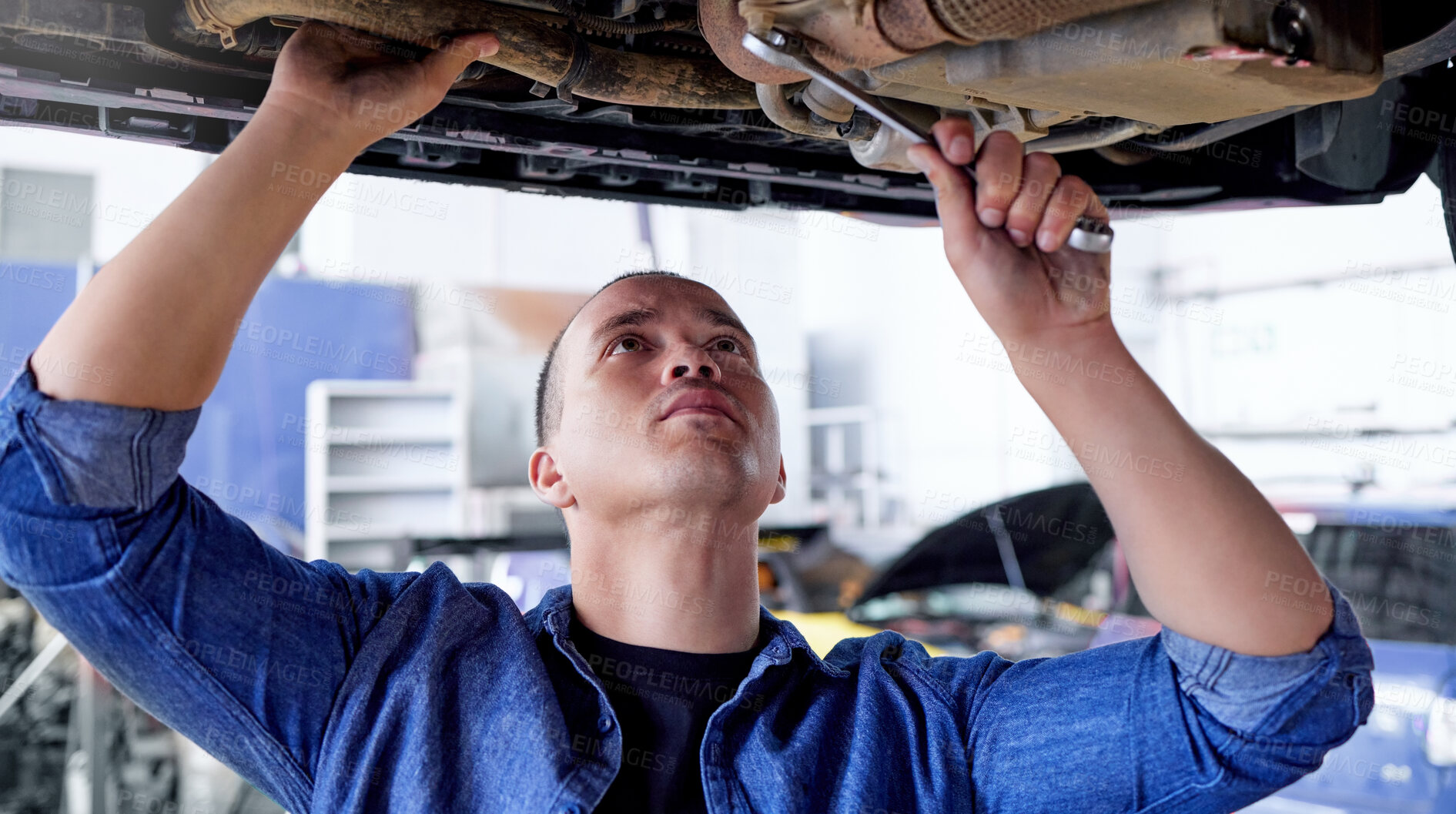 Buy stock photo Mechanic, engineer and car with a man at work in a garage or service center for the transport industry. Workshop, auto and repair with a young male repairman working on a vehicle for maintenance