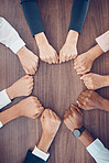 Top view, business people and fist in support circle, team building or collaboration motivation for success goals or target mission. Men, women or worker hands in huddle on table for diversity growth