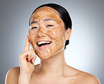 Skincare, portrait and woman with a coffee face mask for fresh, clean and beautiful skin in studio. Beauty, dermatology and happy girl model from Japan with facial scrub isolated by a gray background