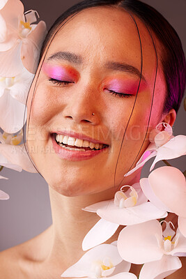 Buy stock photo Beauty, skincare and flowers with a model asian woman in studio on a gray background for health or wellness. Face, cosmetics and treatment with a young female posing to promote a natural product