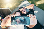 Couple in park, phone selfie and lying on blanket to relax on romantic picnic and spending quality time together. Love, romance and man and woman on grass with picture on smartphone screen and smile.