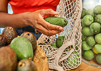 Hands, avocado and bag with a woman customer shopping in a grocery store for a health diet or nutrition. Supermarket, food and retail with a female shopper in a shop produce aisle for groceries