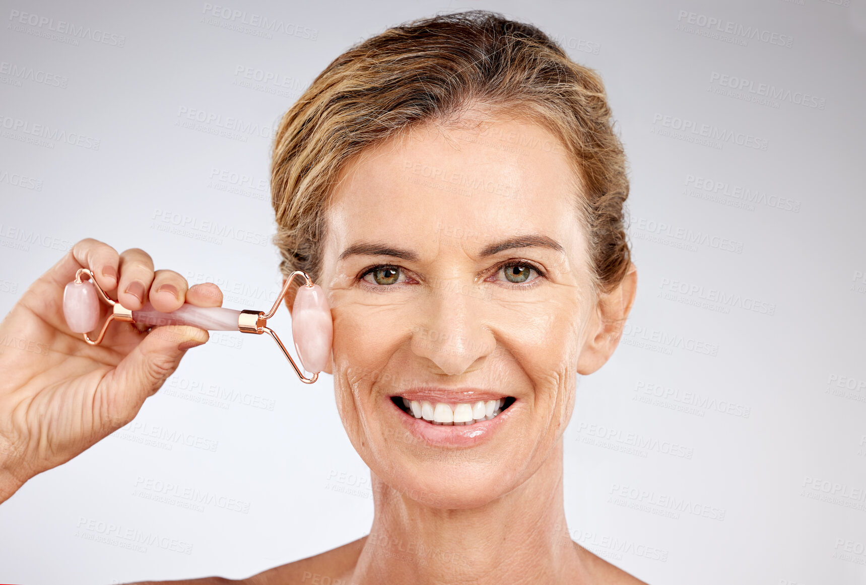 Buy stock photo Beauty, skincare and senior woman with roller or dermatology tool for healthy and wrinkle free skin in studio. Happy lady doing face massage for wellness, health and natural antiaging