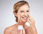 Skincare, elderly and woman with facial cream or face cream product for healthy glowing face in studio portrait. Smile, mockup and happy mature beauty model grooming with sunscreen natural cosmetics