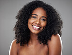Happy, smile and portrait of a young woman with clean, beautiful and natural hair in a studio. Happiness, beauty and face of girl model with afro from Brazil smiling while isolated by gray background