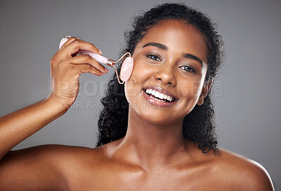 Buy stock photo Skincare, portrait and woman with a face roller for wellness, beauty and skin routine in studio. Happy, smile and girl model from Brazil with rose quartz cosmetic tool for self care facial treatment.
