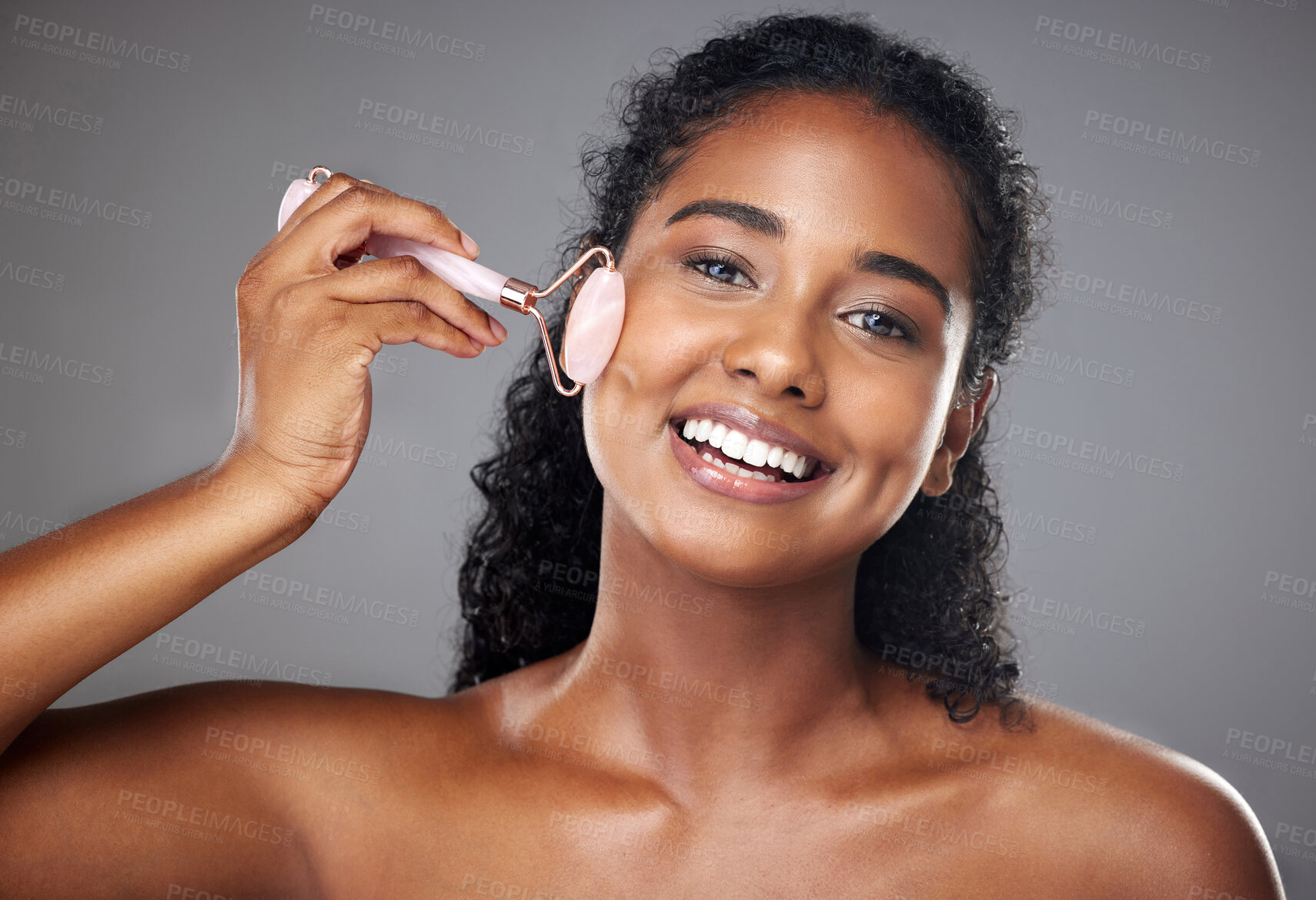 Buy stock photo Skincare, portrait and woman with a face roller for wellness, beauty and skin routine in studio. Happy, smile and girl model from Brazil with rose quartz cosmetic tool for self care facial treatment.