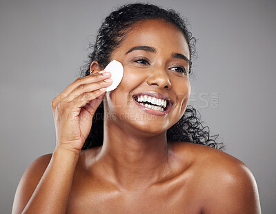 Buy stock photo Skincare, cotton pad and woman cleaning face with a smile against a grey studio background. Clean, wellness and African girl model thinking of facial makeup, cosmetic cleansing and care for skin
