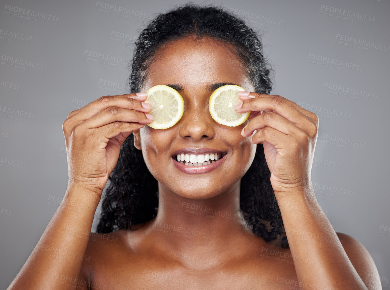 Buy stock photo Skincare, portrait and woman with lemon on her eyes for health, beauty and wellness standing in a studio. Happy, smile and face of girl model from Brazil with citrus fruit isolated by gray background