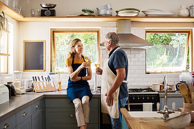 Buy stock photo Love, wine and mature couple in kitchen cooking, drinking and spending free time together in home. Retirement, happy man and woman with wine glass, smile and apron relax before dinner in modern house