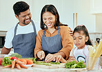 Family, food and cooking in kitchen for health, wellness and nutrition with vegetables and happy people. Happy family, girl and parents bonding while preparing a balanced meal in their home together