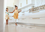 Hopscotch, fun and children playing a game together in the kitchen of their modern family home. Happy, smile and girl kids or sisters jumping on numbers to play, bond and for entertainment at a house