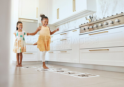 Buy stock photo Hopscotch, fun and children playing a game together in the kitchen of their modern family home. Happy, smile and girl kids or sisters jumping on numbers to play, bond and for entertainment at a house