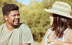 Happy, love and couple in nature in a conversation while on an outdoor garden picnic date in summer. Happiness, communication and young man and woman with a smile talking in a park to relax together.