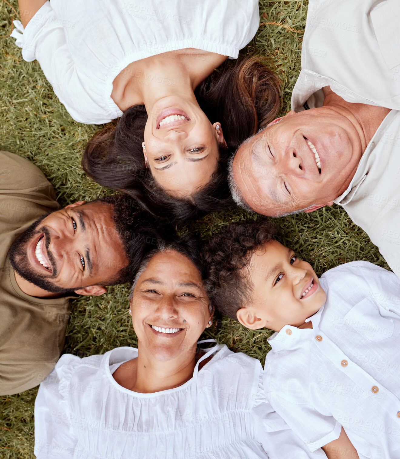 Buy stock photo Big family, face and portrait smile above relaxing in quality bonding time together on the grass in the outdoors. Happy family smiling in joyful happiness lying in relax for summer break in the park