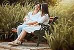 Women, baby care and outdoor nature park of a mother, child and friend talking together. New mama and a woman spending quality time talking about motherhood in the summer sun by green plants