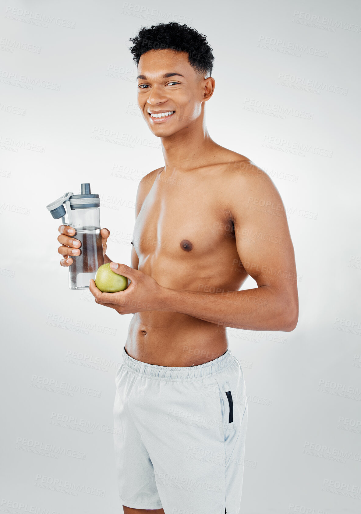 Buy stock photo Fitness, apple and man drinking water in studio after training, cardio workout and exercise for body wellness. Lifestyle, fruit and healthy young athlete or happy personal trainer on a vegan diet